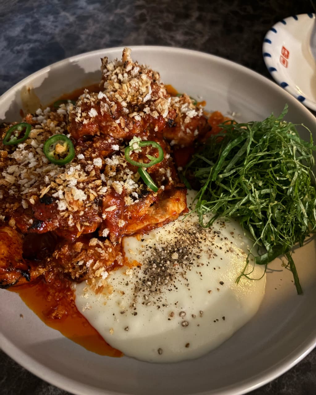 인천광역시 부평구 요리주점 스몰톡소셜클럽 인천 - 어두운 조명 아래 다찌석 혼술 메뉴로 나온 바삭한 가루를 얹은 매운 고기와 부드러운 퓌레, 채 썬 깻잎