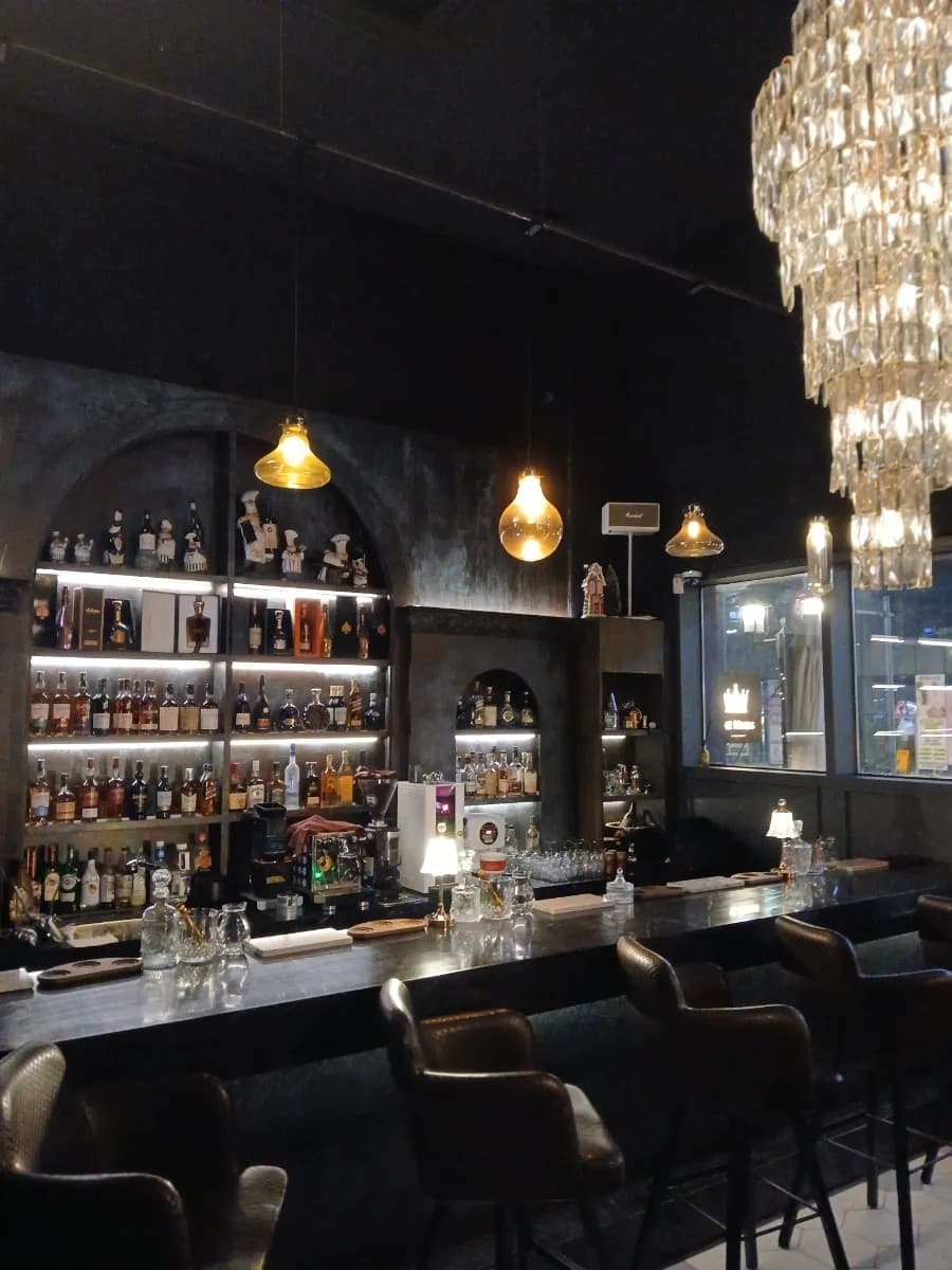인천광역시 연수구 혼술 바(Bar) 더킹스 송도술집 인천 - 오렌지빛 조명 아래 긴 다찌석과 위스키 진열장, 가죽 의자가 배치된 1인 전용 공간