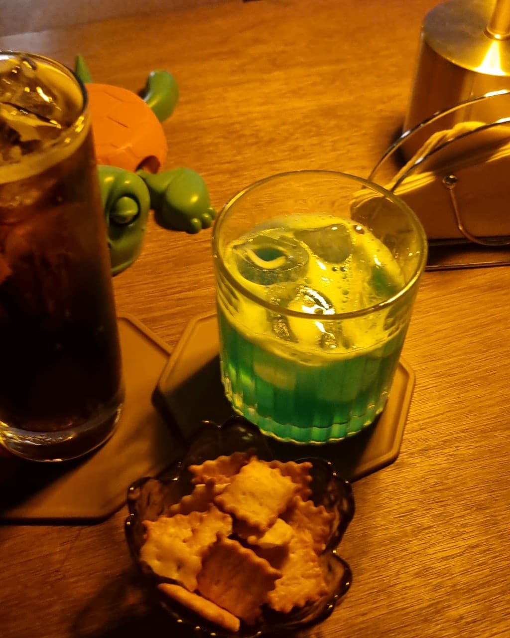 제주특별자치도 서귀포시 혼술바 고도 서귀포점 제주 바(Bar)의 다찌석 노란 조명 아래 놓인 푸른 칵테일과 크래커. 혼술을 위한 1인석 테이블 위 차려진 술자리 상황.