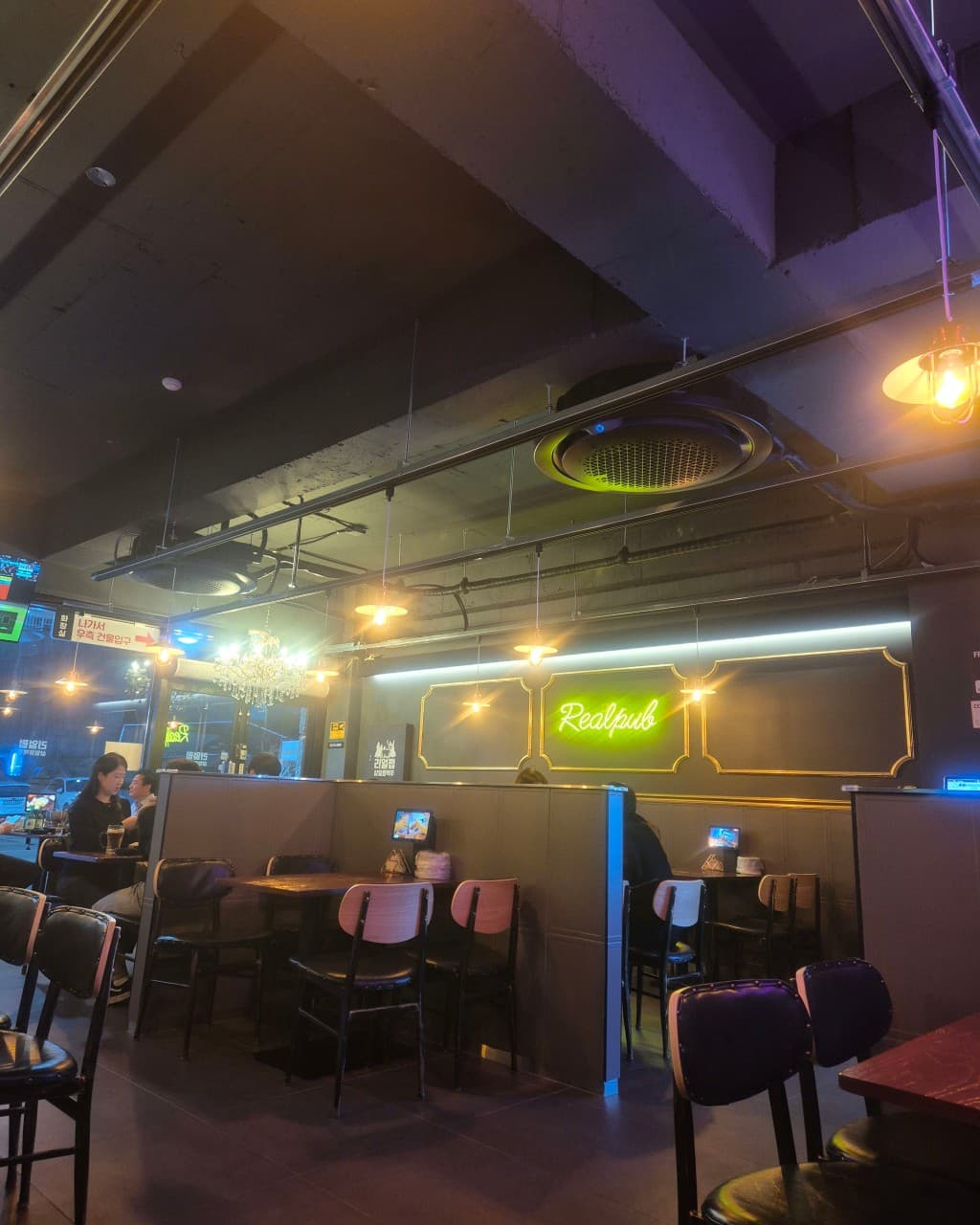 강원특별자치도 춘천시 리얼펍 춘천온의점 맥주 호프 - 네온사인과 노란 조명 아래 칸막이 좌석에서 1인 혼술을 즐기는 차분한 공간 모습