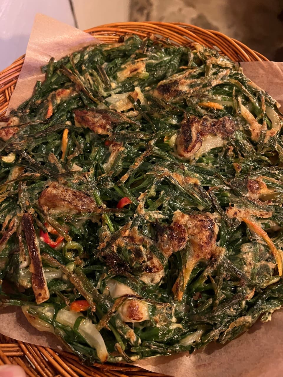 강원특별자치도 속초시 청학동사거리 전통주점 다찌석에서 노란 조명 아래 채반에 담긴 바삭한 부추전을 즐기는 1인 혼술 상황.