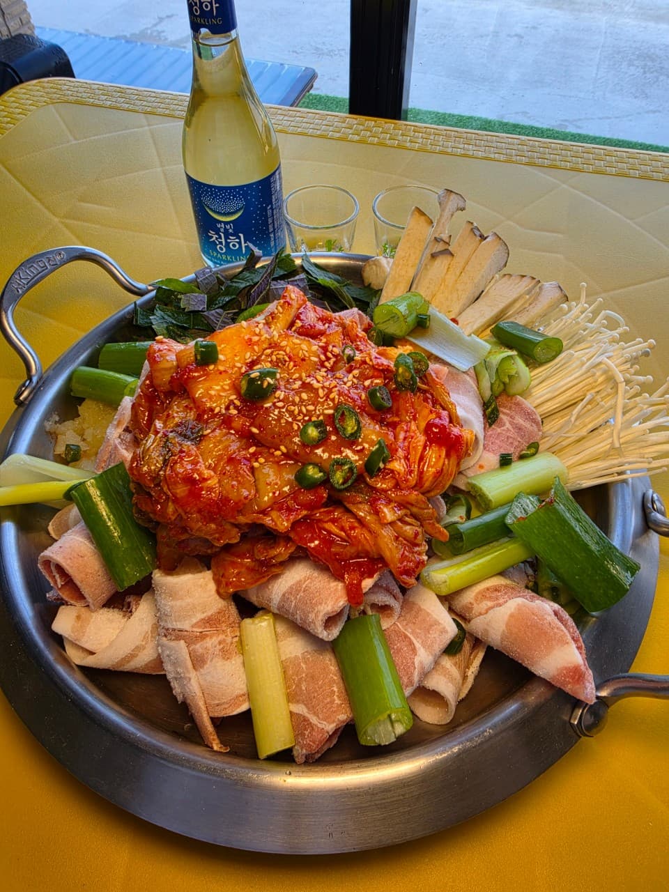 강원특별자치도 동해시 어달 옆 포차 포장마차 혼술. 노란 테이블 위 선홍빛 삼겹살과 양념된 김치, 대파가 수북한 전골 냄비와 별빛청하가 차려진 1인 식사 구성.