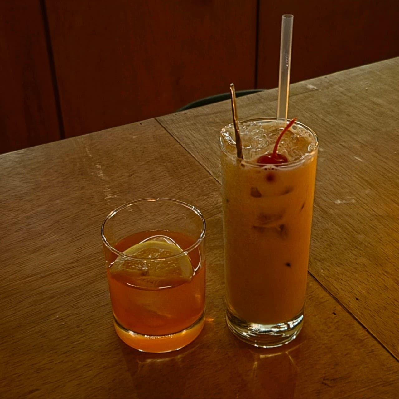 강원특별자치도 원주시 원주혼술바 잔담 바(Bar) 나무 다찌석 위 노란 조명을 받은 레몬 조각과 체리가 담긴 칵테일이 놓인 1인 혼술 상황