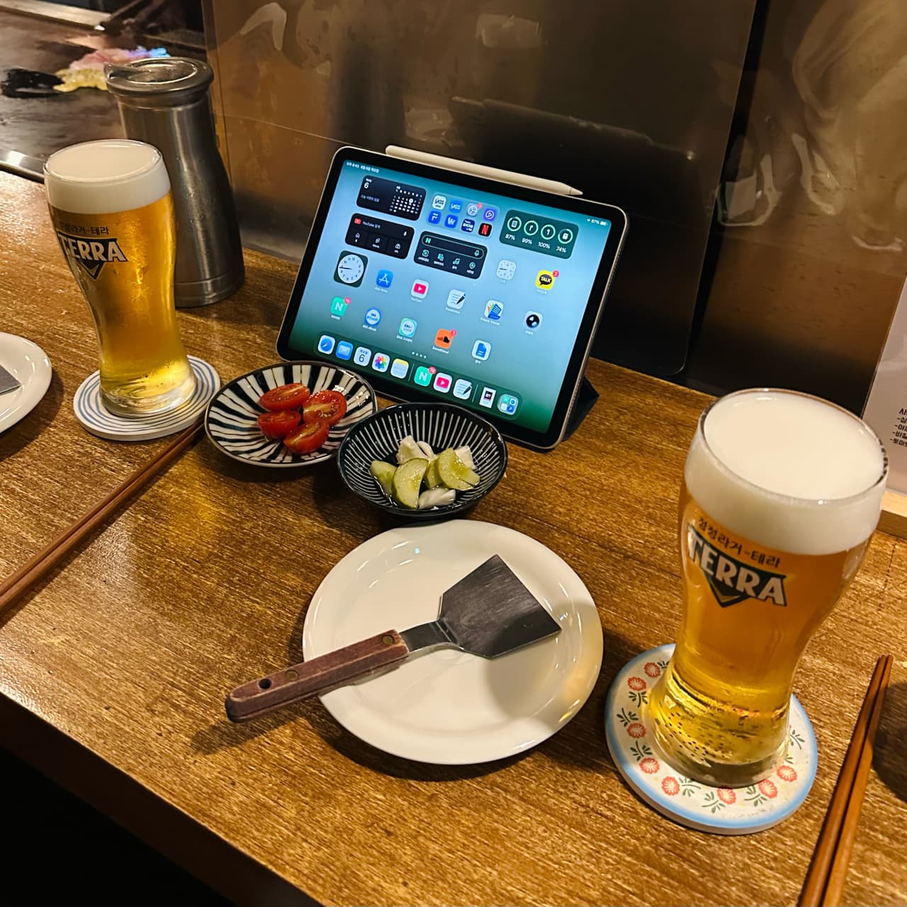 강원특별자치도 원주시 이자카야 온점 - 낮은 조도의 다찌석 위 테라 생맥주와 토마토 절임, 태블릿이 차려진 1인 혼술 상황