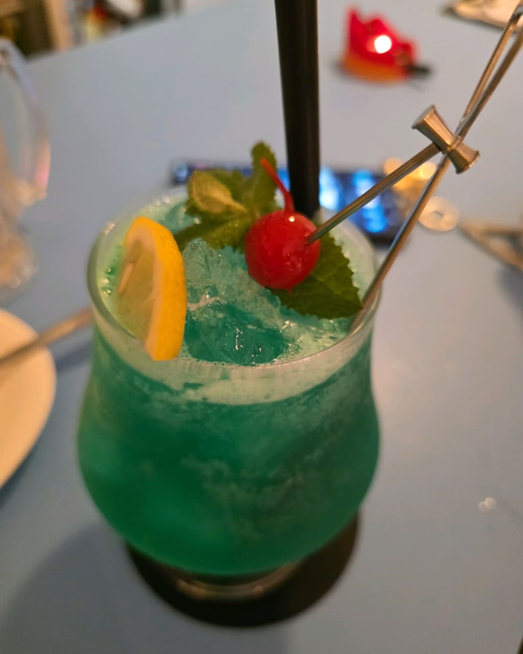 강원특별자치도 속초시 미드나잇썸머 바(Bar) 1인 테이블 위 레몬과 체리를 곁들인 푸른색 칵테일과 붉은 조명이 놓인 혼술 상황