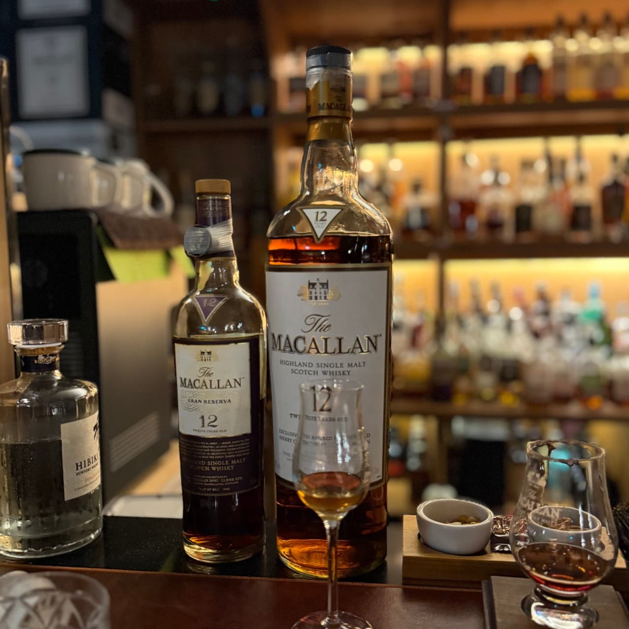 강원특별자치도 춘천시 몰트앤뮤직 바(Bar) 카운터 다찌석에 놓인 맥캘란 위스키와 전용 잔. 주황빛 조명 아래 1인 혼술을 즐기는 위스키 바의 테이블 구성.