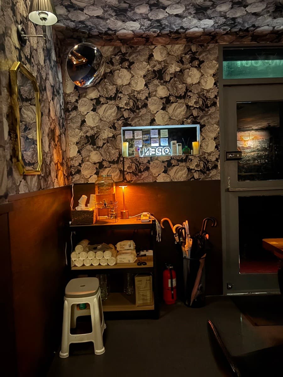 경상남도 창원시 도트 창원혼술바 상남점 바(Bar) - 꽃무늬 벽지와 오렌지색 조명 아래 1인석 의자와 서비스 선반이 배치된 혼술 공간