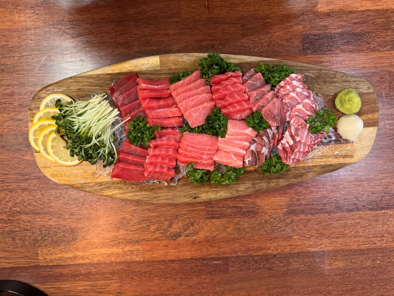 경상남도 김해시 튜나펍 김해주촌점 다찌석 1인 혼술. 나무 판 위 선홍빛 참치 회와 레몬, 무순의 질감이 드러나는 구성. 조명 아래 가지런히 차려진 기타 안주류 메뉴.