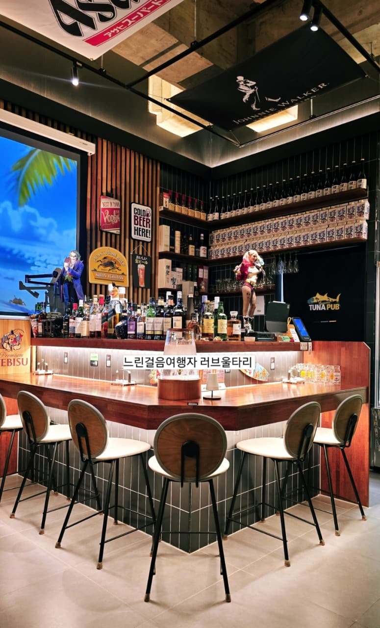 경상남도 김해시 튜나펍 김해주촌점 목재 카운터 다찌석과 주류 선반. 혼술을 위한 1인석 의자와 간접 조명이 비치는 기타 일식 펍의 바 테이블 좌석 배치.
