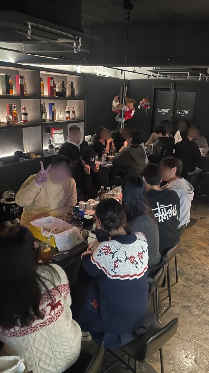 경상남도 창원시 꼼바혼술바 창원상남점 바(Bar) - 어두운 조명 아래 술병이 진열된 선반과 긴 다찌석에서 혼술을 즐기는 사람들