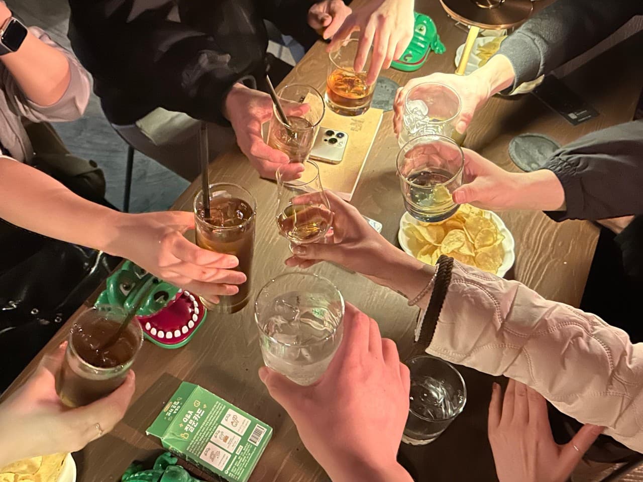 충청북도 청주시 야화 혼술바 청주율량점 바(Bar) 다찌석에서 하이볼과 위스키 잔을 부딪치는 상황. 노란 조명 아래 감자칩이 놓인 테이블에 1인 손님들이 모여 있는 분위기.