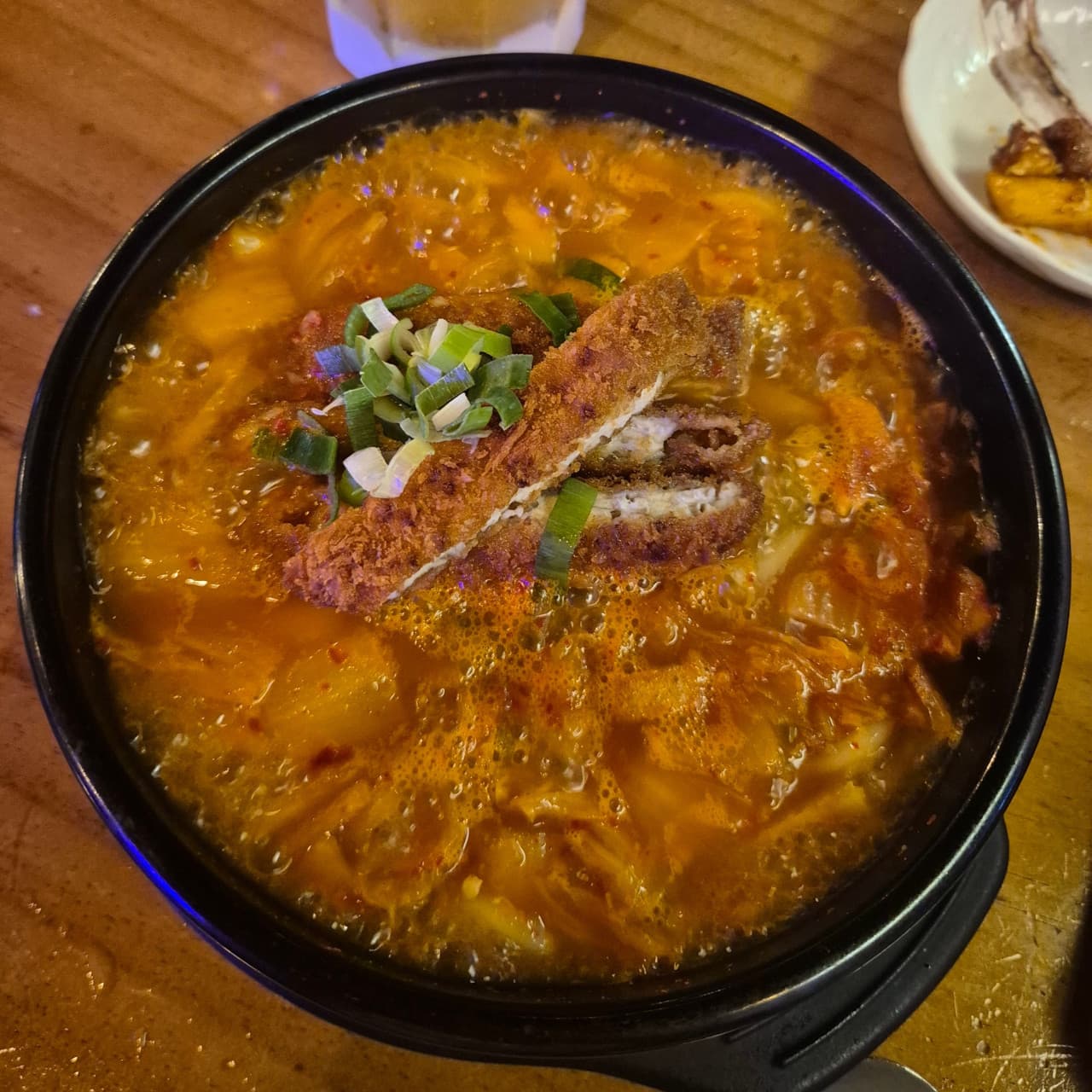 서울특별시 동작구 역전할머니맥주 서울남성역점 맥주,호프 매장. 나무 테이블 위 김치나베와 돈가스 안주 1인 혼술 상차림. 조명 아래 뚝배기 속 국물과 튀김 질감이 강조됨.