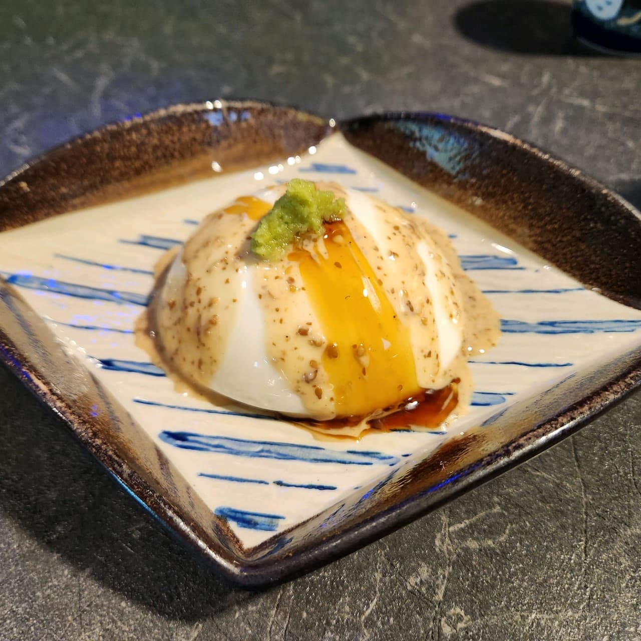 서울특별시 동작구 이자카야민 혼술 이자카야 다찌석 위 조명을 받은 모찌리도후. 소스가 뿌려진 탱글한 질감의 안주와 와사비가 차려진 1인 식사 상황.